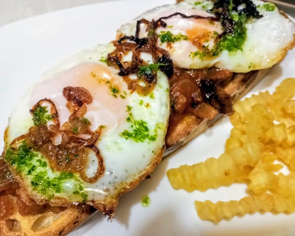 tosta manchega con pisto, huevos fritos y cebolla caramelizada